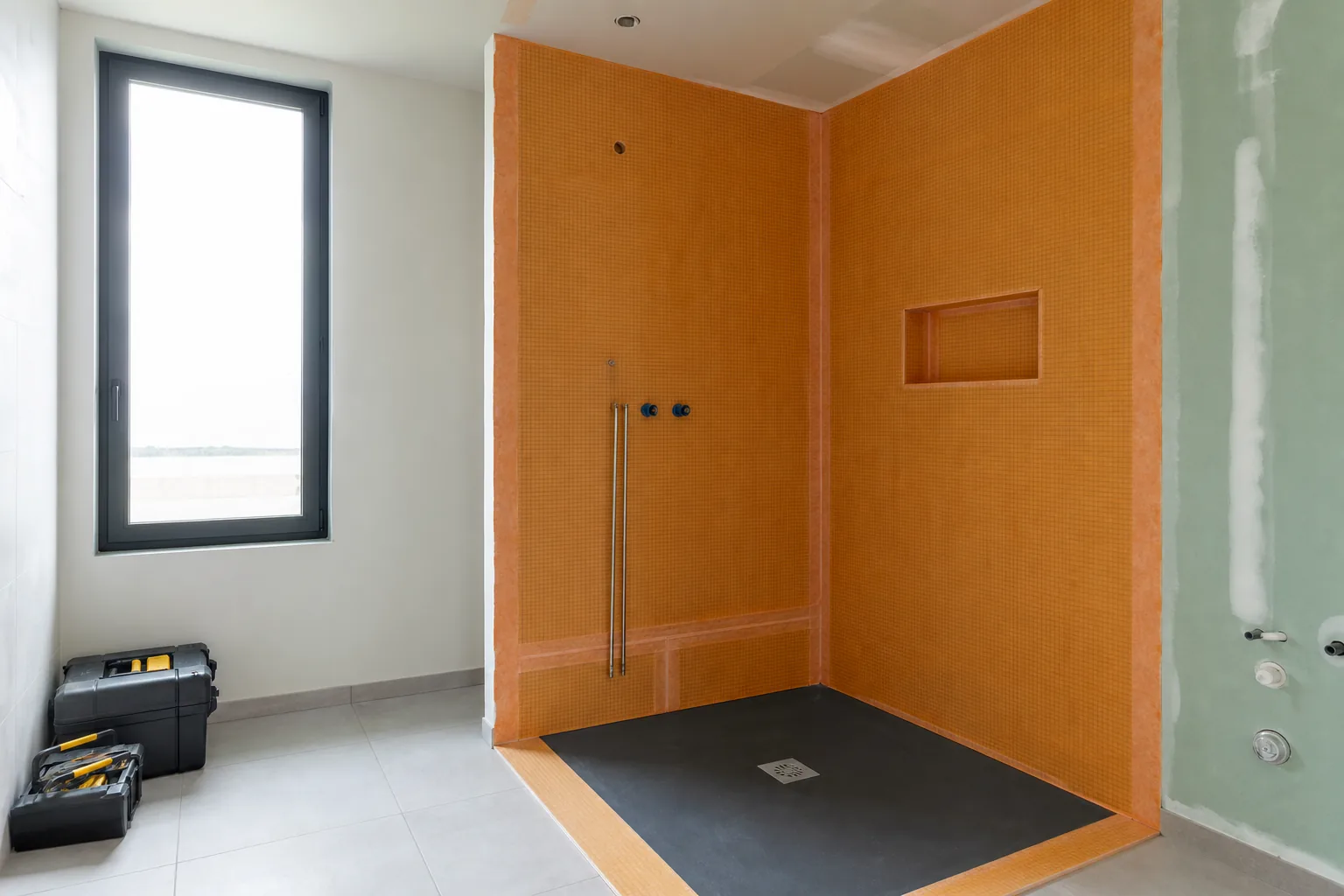Douche à l’italienne en cours de pose, receveur et natte d’étanchéité visibles avant carrelage, outillage rangé, chantier propre