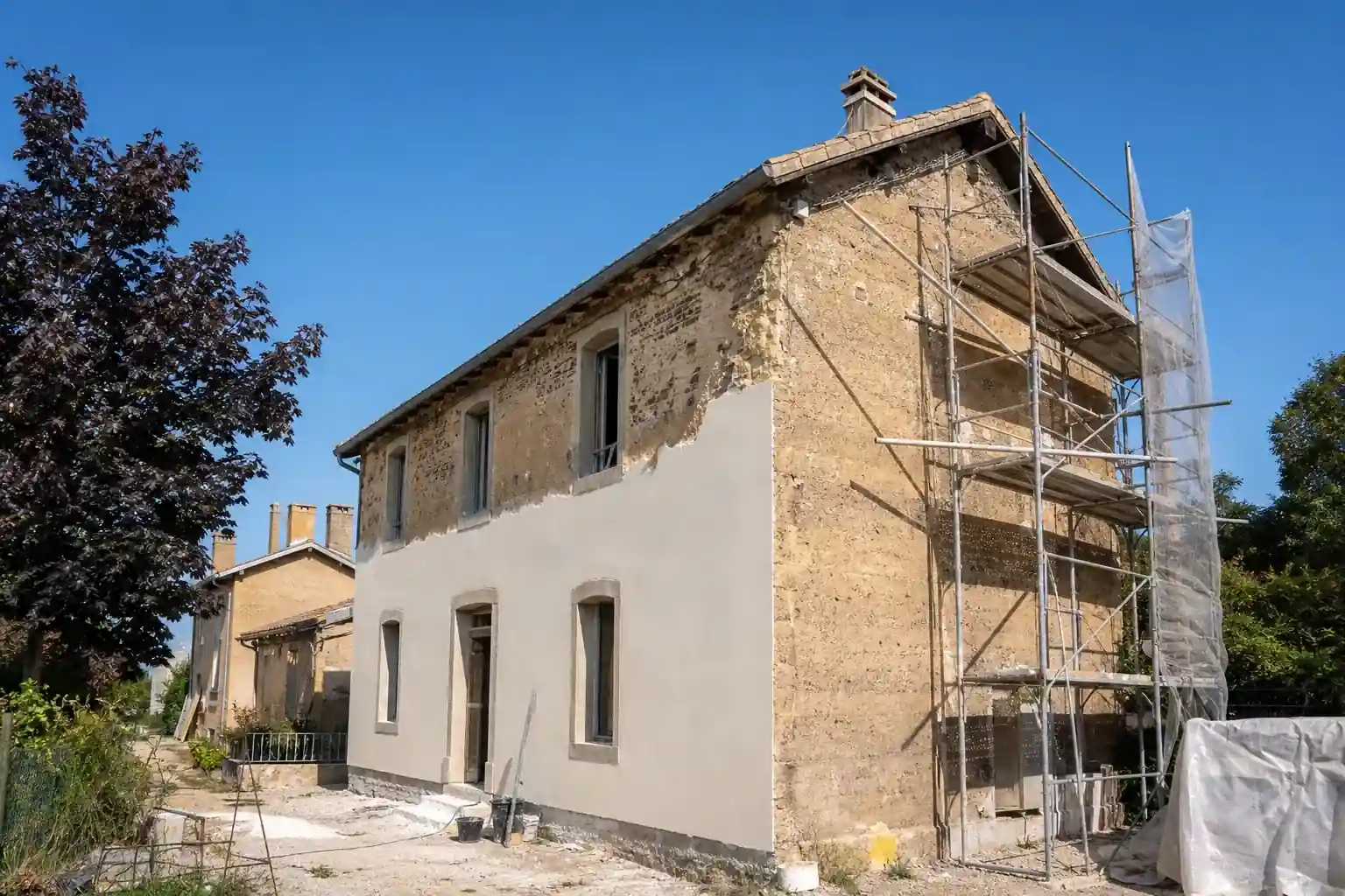 Maison ouvrière du Carmausin à Blaye-les-Mines en cours de rénovation, échafaudage sur pignon, enduit neuf à mi-façade, ciel dégagé