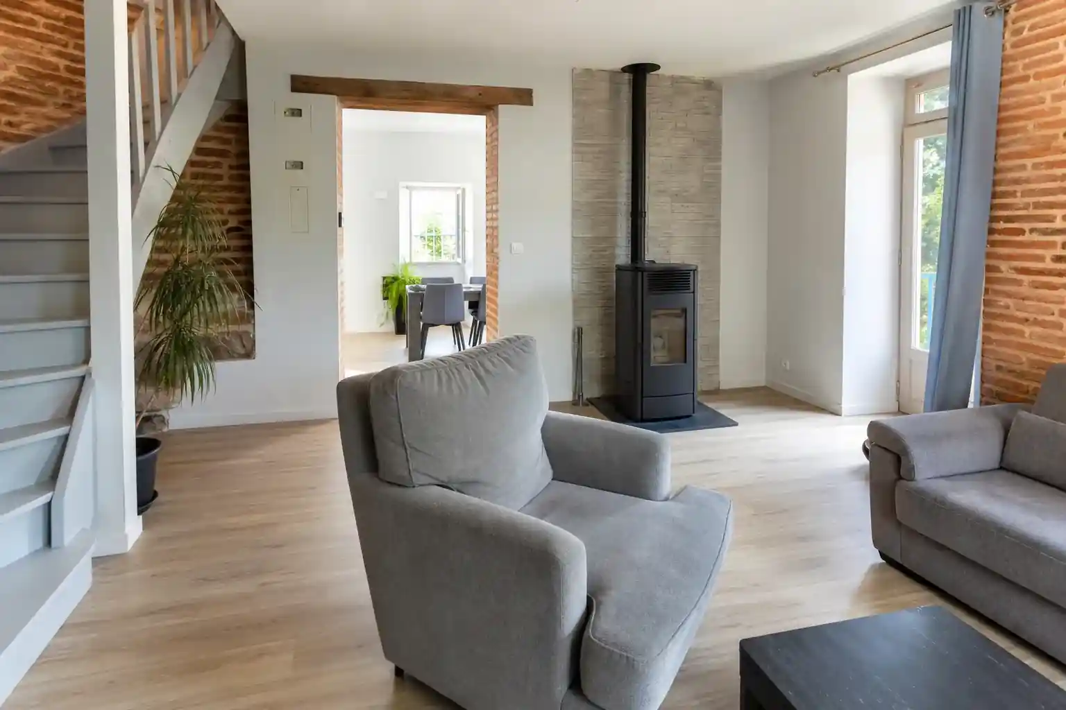 Pièce de vie rénovée dans une maison du Carmausin, sol stratifié clair, poêle à granulés, escalier repeint