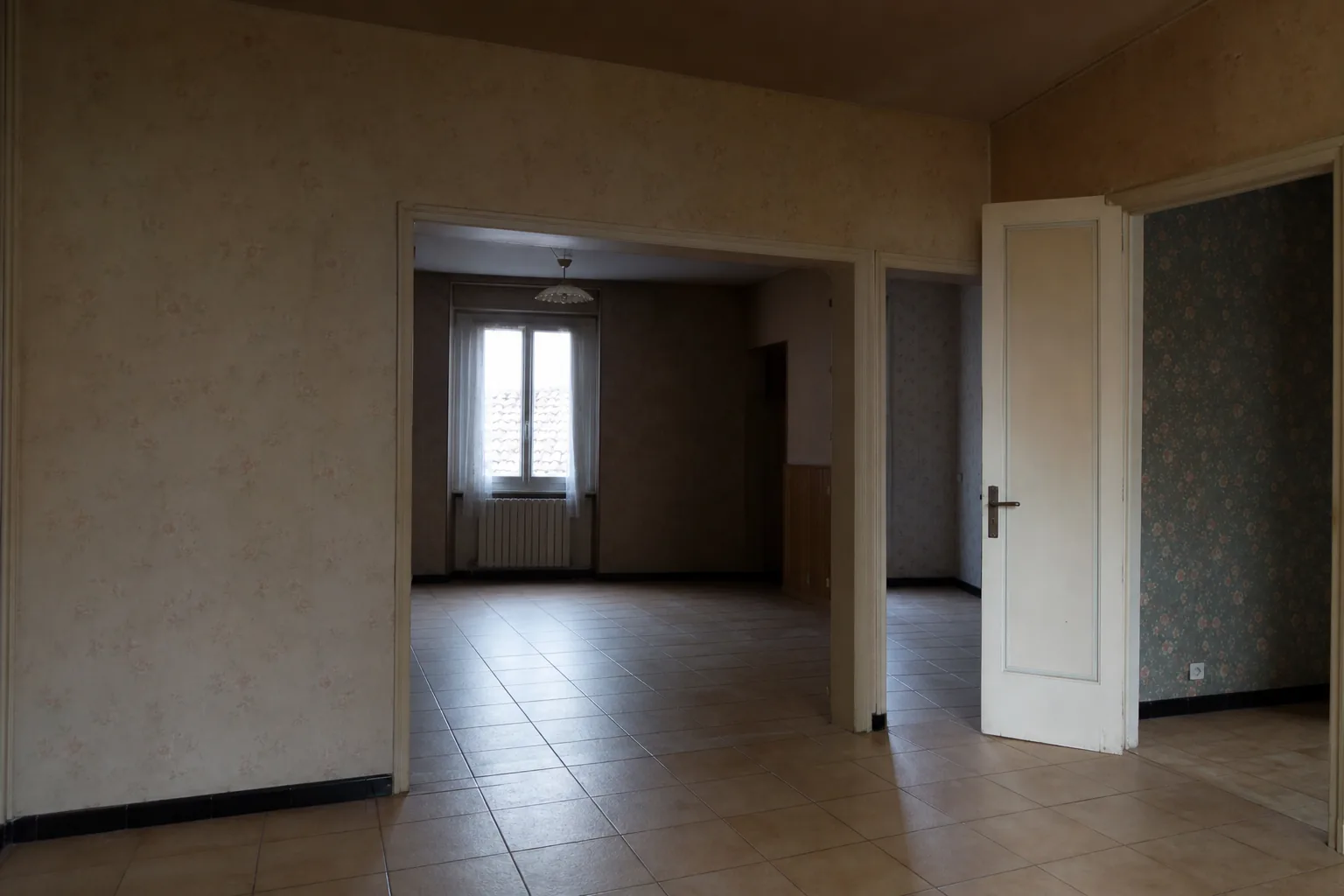 Pièce de vie sombre et cloisonnée d’une maison de ville albigeoise avant travaux, papier peint daté, sol carrelage 90