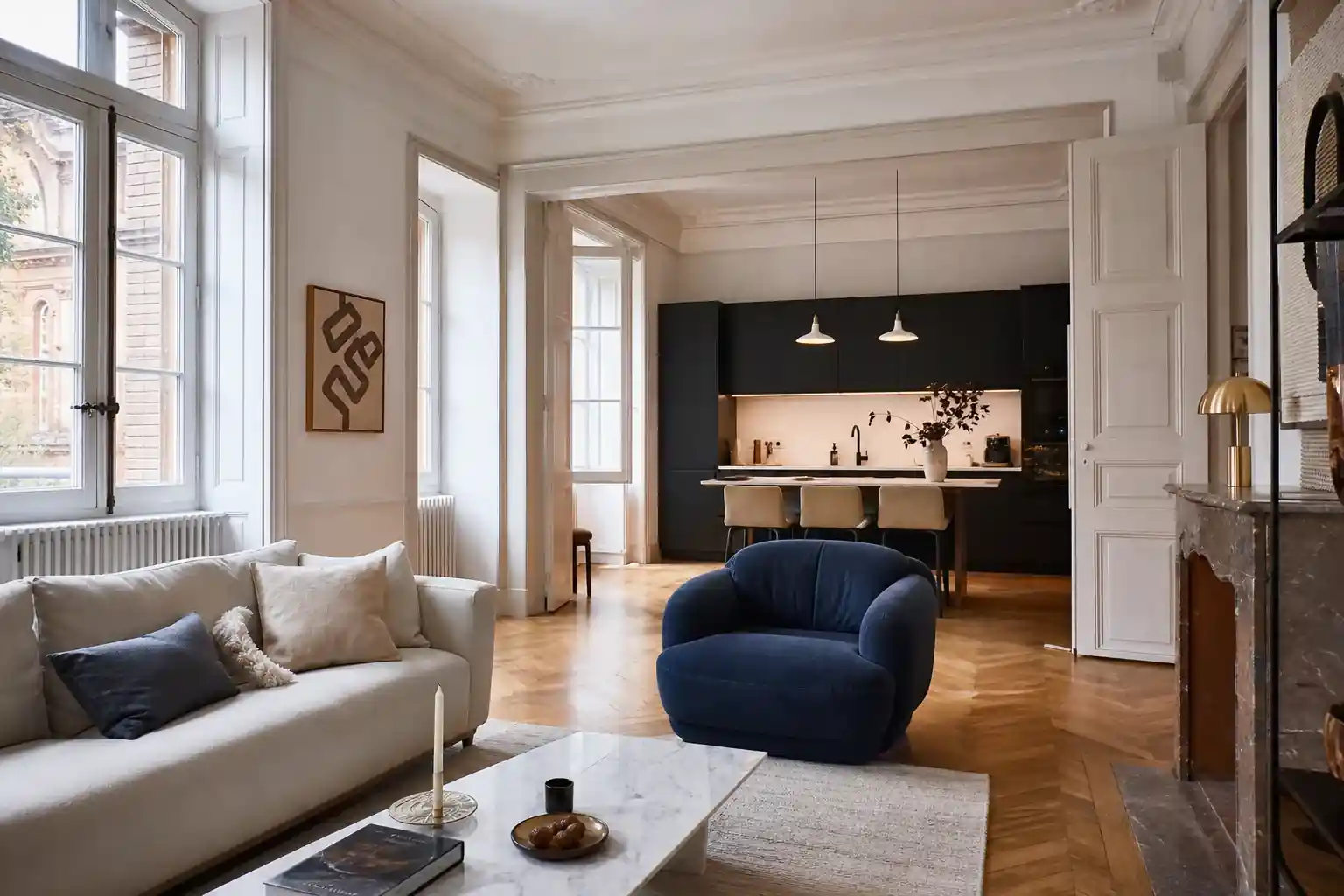 Séjour d’appartement rénové dans un immeuble ancien d’Albi, hauteur sous plafond généreuse, moulures repeintes, parquet restauré, cuisine ouverte discrète