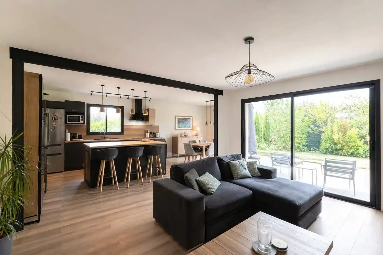 Séjour de pavillon ouvert sur la cuisine après démolition d’une cloison, baie vitrée neuve sur jardin arboré de Puygouzon
